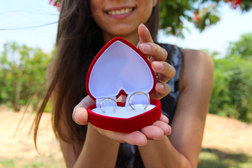 women hands with a velvet red box with a pair of gold wedding rings