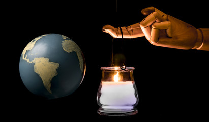 Giant hand illuminates the Earth with a candle for wisdom and knowledge. Isolated on dark background. Studio Shot. Isolated on black background.