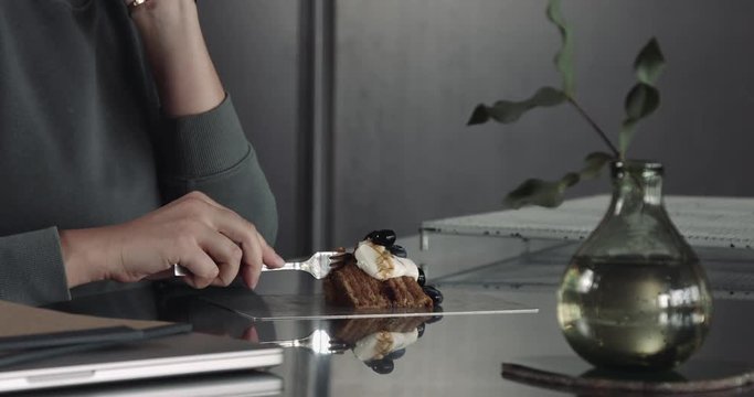 womantake a slice of cake, eats blueberry with cream and then put a fork on the table
