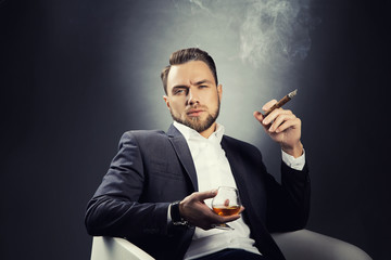 Portrait of young man with cognac glass and cigar