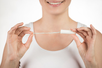 A young girl is holding a hygienic tampon showing a thumbs up on a white background