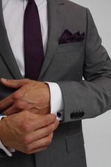 Close up of a man in suit. Man is holding cuff of suit