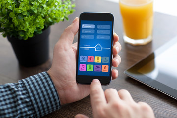 man holding phone with app smart home over desk