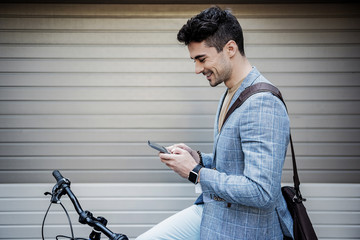 Merry smiling male person typing on smartphone