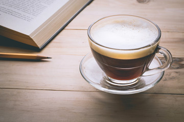 Coffee cup with book on wood table in morning