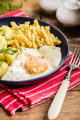 Fried egg served with potatoes and yellow beans.