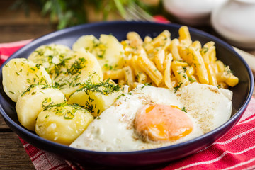 Fried egg served with potatoes and yellow beans.