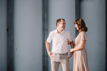 beautiful couple on a walk, the girl in the beige dress and the guy wearing light clothing in the Park near the high grey iron pipes, summer, nature, love story, family, values