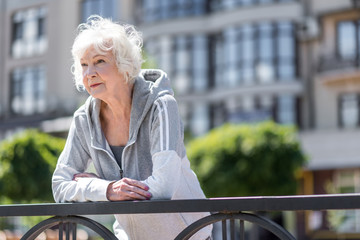 Joyful old beautiful lady having rest during morning exercise outside