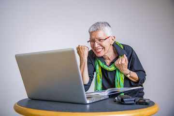 Senior grey haired woman cheering victoriously for receiving great news