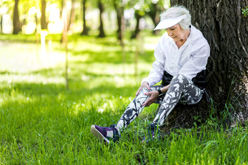 Serious old woman recreating after training in green forest