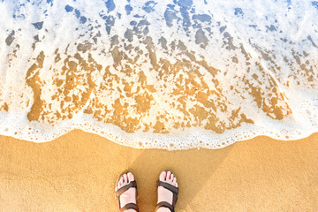 Woman's feet in sandals on a beach sand