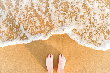 Woman's feet on yellow beach sand
