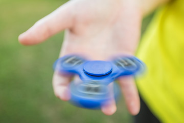 Girl's hand holding a spinning fidget spinner in her hand, spinning them on her middle finger