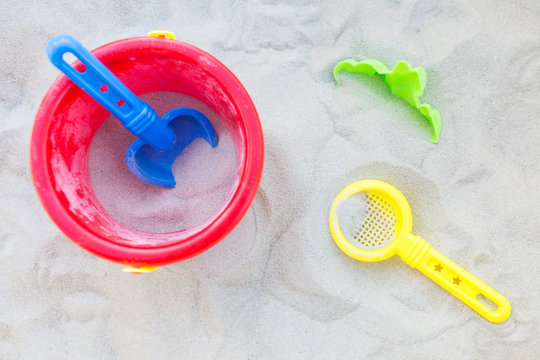 Plastic bucket, sifter and a small shovel in the sand; view from above