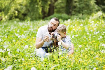 Fototapeta premium Young father with little boy with camera in summer park.