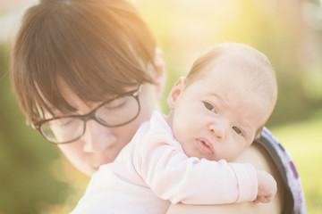 Mother holding her newborn baby daughter; concept of parenthood, happiness and family life.