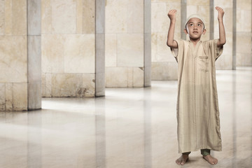Little asian muslim boy raising hand and praying