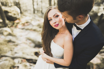 Gorgeous bride, groom kissing and hugging near the cliffs with stunning views