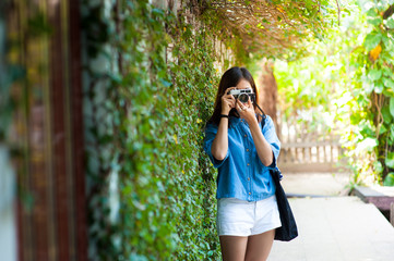 Hipster woman taking photos with retro film camera in flower garden of city park,beautiful girl photographed in the old camera.