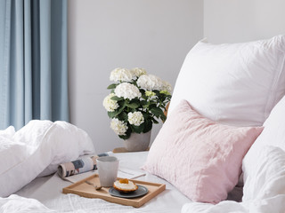 frühstück im Bett mit Holztablett, Zeitung und Blumen