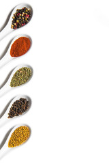 Top view of assorted aromatic seasonings in ceramic spoons isolated on white