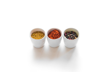 Close-up view of assorted aromatic dried spices in ceramic bowls isolated on white