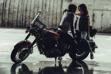 Sensual stylish young couple sitting on motorcycle and looking at each other