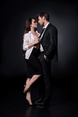 young sexy woman seducing young man in suit isolated on black