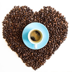 Heart of coffee beans with azure blue cup isolated on white background