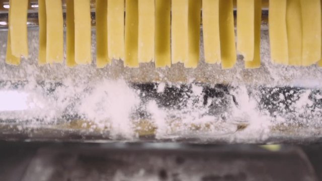 Pasta machine makes pasta from dough, slow-motion shooting.  50fps. Close-up.
