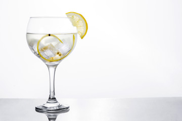 Glass of gin tonic with lemon on white background