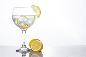 Glass of gin tonic with lemon on white background