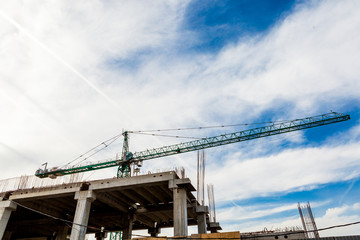 Crane on construction site on blue sky with clouds. Construction and building