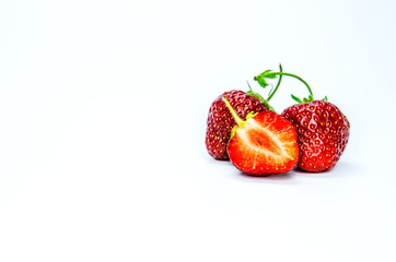 Two red whole ripe strawberry berries and one cut on a white background.