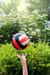 volleyball fight off the hands of a teenager against the bright of blooming greenery and sunlight