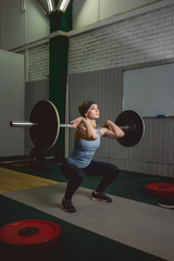 Strong woman lifting barbell as a part of crossfit exercise routine