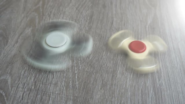 two white hand spinner spinning on grey background or fidget spinners.