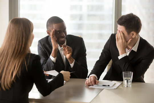 Multiracial businessmen hiding face with hands, sneaking look at each other while businesswoman presenting document, recruiters covertly discussing candidate, secretly whispering during interview