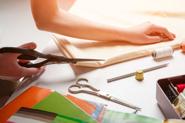 Crop woman cutting fabric