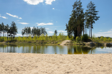 Bright landscape in a sunny day. A small pond in countryside with sand on a foreground and pines and birches on a background. - 159288534