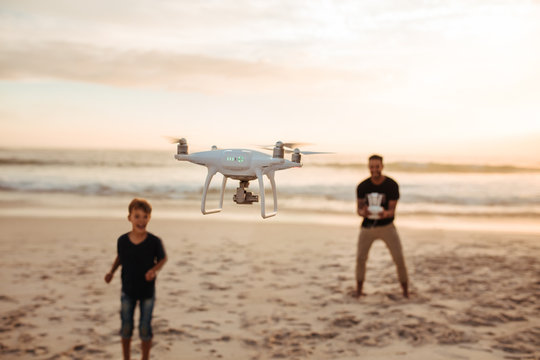 Father and son on summer vacation flying drone on beach