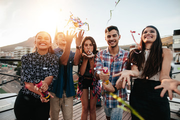 Young people enjoying rooftop party with confetti - obrazy, fototapety, plakaty