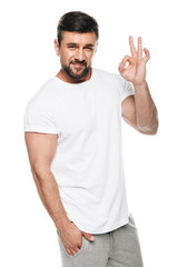 Portrait of handsome man in white t-shirt gesturing ok sign isolated on white