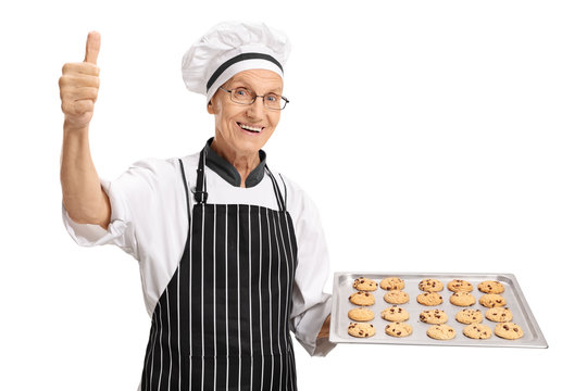 Baker holding tray with cookies and making thumb up sign