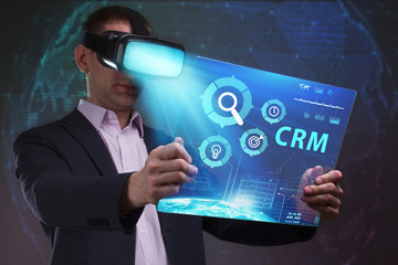Business, Technology, Internet and network concept. Young businessman working in virtual reality glasses sees the inscription: CRM