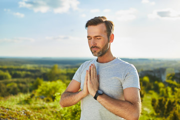 Adult man medittating  praying outdoors - serenity concept