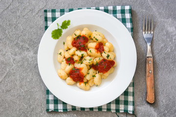 Gnocchi with tomato sauce on gray stone
