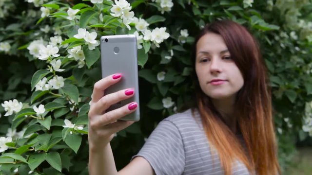 A young girl takes pictures of herself on a mobile phone, smartphone, camera.