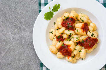 Gnocchi with tomato sauce on gray stone

